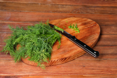 Sprigs of fresh green dill and knife on wooden tableの写真素材