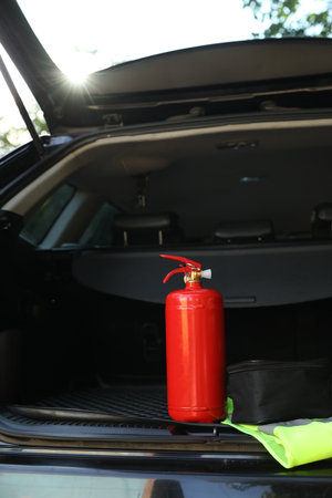 Red fire extinguisher in trunk. Car safety equipment