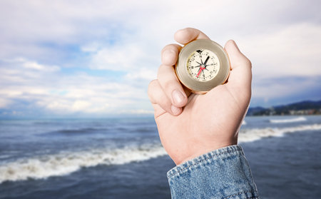 Man holding compass on beach near sea, closeup. Space for textの写真素材