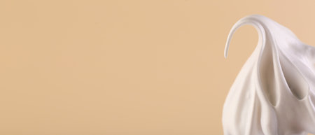 Whisk with beaten cream on dark beige background, closeup. Banner design, space for text