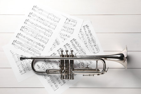 Trumpet and music sheet papers with notes on white wooden table, flat layの写真素材