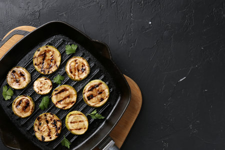 Tasty grilled zucchini slices with parsley in frying pan on gray textured table, top view. Space for textの写真素材
