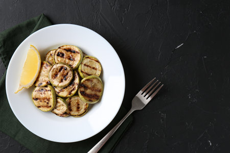 Tasty grilled zucchini slices served on black textured table, flat lay. Space for textの写真素材