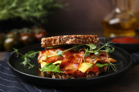 Tasty sandwich with bacon and cheese on wooden table, closeup