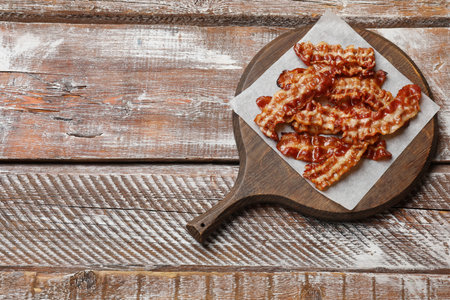 Slices of tasty fried bacon on wooden table, top view. Space for textの写真素材