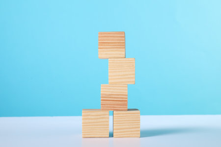 Stack of wooden cubes on white table against light blue backgroundの写真素材