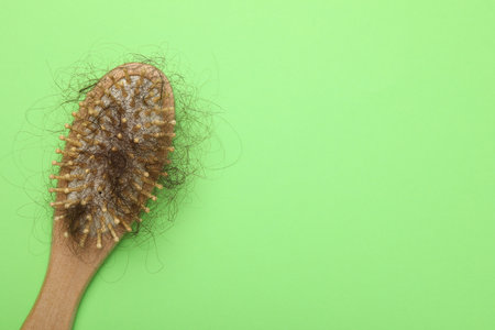 One brush with lost hair on light green background, top view. Space for text