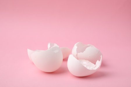 Pieces of broken eggshells on pink background, closeup