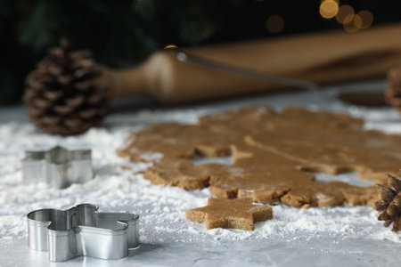Raw dough and cookie cutters on grey table, closeup
