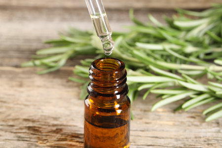 Dripping essential oil into bottle on wooden table, closeupの写真素材
