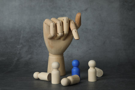Blue piece among wooden ones and hand figure on grey table