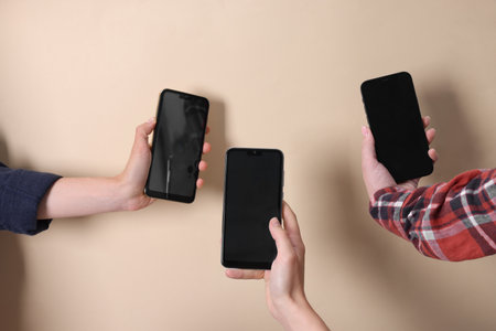 Women holding smartphones with blank screens against beige background, closeup. Mockup for designの写真素材