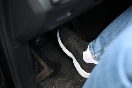 Man pushing on pedal of car brake, closeup
