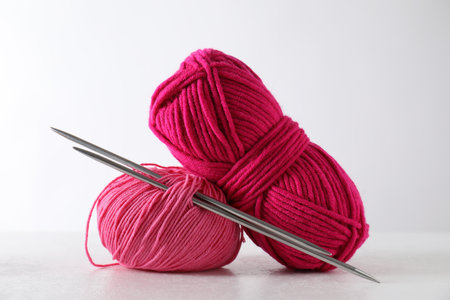 Two soft skeins of yarn and knitting needles on light gray backgroundの写真素材