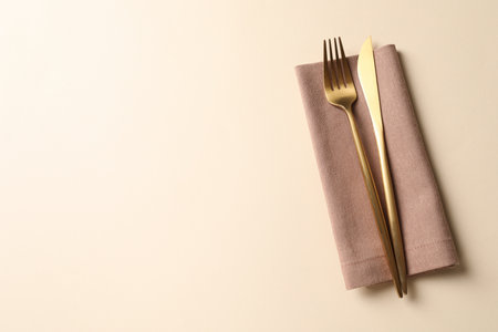 Stylish golden cutlery and napkin on beige background, top view. Space for textの写真素材