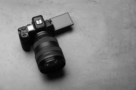 Modern photo camera on gray table, space for text. Photographer's equipmentの写真素材