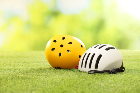 White and yellow protective helmets on green grass, space for text