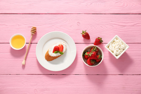 Delicious ricotta bruschetta with strawberry and mint on pink wooden table, flat layの写真素材
