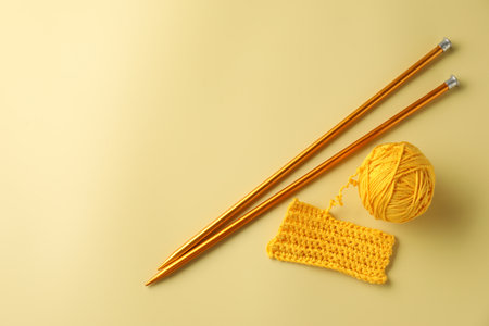 Ball of yarn, pattern sample and knitting needles on yellow background, flat lay. Space for textの写真素材