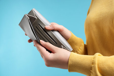 Woman with empty wallet on light blue background, closeupの写真素材