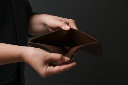Woman with empty wallet on dark background, closeupの写真素材