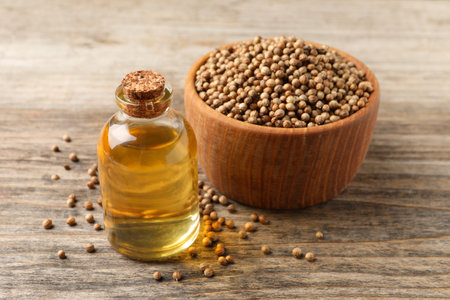 Coriander essential oil and seeds on wooden tableの写真素材