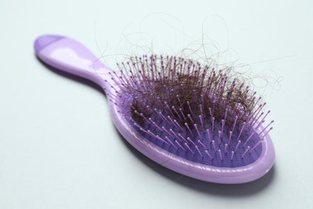 One brush with lost hair on gray background, closeup. Alopecia problem