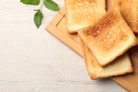 Slices of delicious toasted bread on wooden table, top view. Space for text