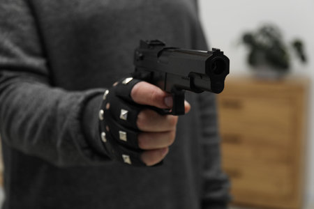Dangerous criminal with gun indoors, closeup. Armed robbery