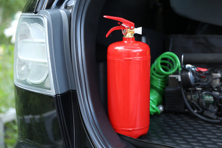 Red fire extinguisher in trunk. Car safety equipment
