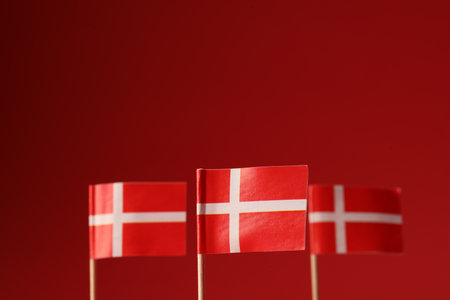Small paper flags of Denmark on red background, selective focus. Space for textの写真素材
