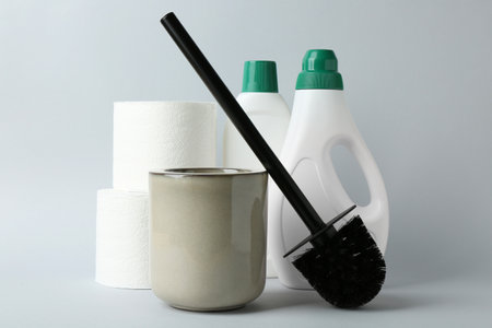 Toilet brush, holder, paper rolls and bottles of cleaning products on white backgroundの写真素材