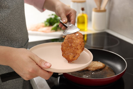 Woman cooking schnitzels in frying pan on stove, closeupの写真素材