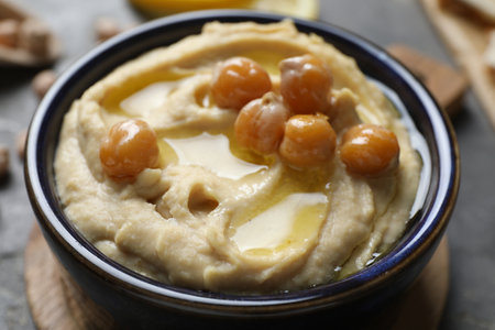 Delicious hummus with olive oil and chickpeas in bowl on gray table, closeupの写真素材