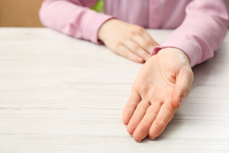 Chiromancy and foretelling. Woman showing palm at white wooden table, closeup. Space for textの写真素材
