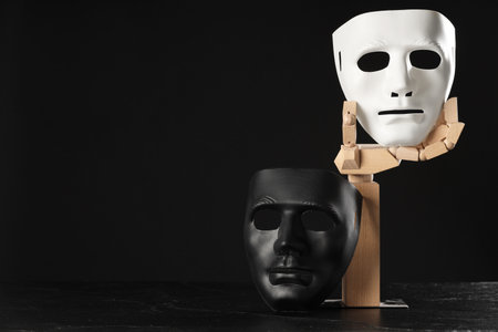 Wooden mannequin hand and plastic masks on black background, space for text. Theatrical performanceの写真素材