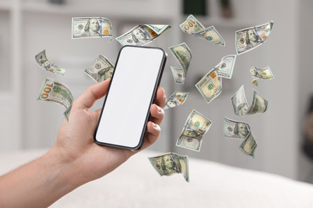Man using smartphone at home, closeup. Money flying around device