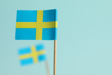 Small paper flags of Sweden on light blue background, selective focus. Space for textの写真素材