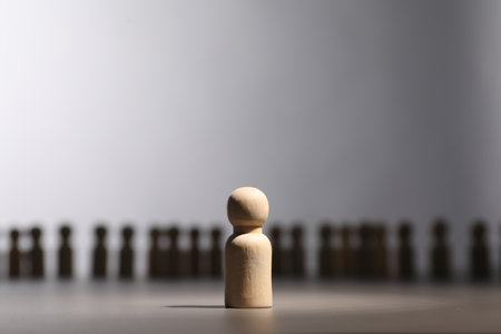 Loneliness concept. Human figure distant from others on gray backgroundの写真素材