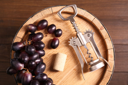 Wing corkscrew, cork, grapes and barrel on wooden table, top viewの写真素材