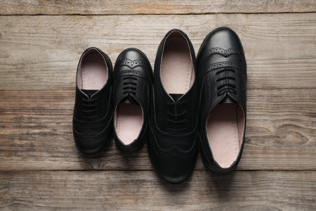Big and small shoes on wooden table, top view