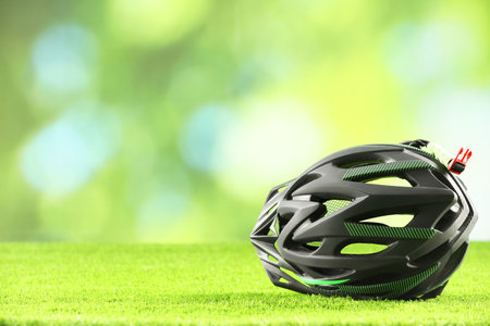 Stylish protective helmet on green grass against blurred background. Space for textの写真素材