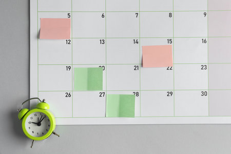 Timetable. Planner with sticky notes and alarm clock on gray table, top view