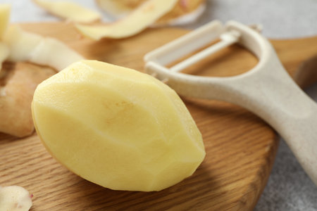 Fresh raw potato and peeler on table, closeupの写真素材