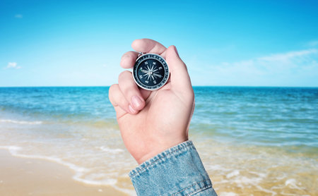 Man holding compass on beach near sea, closeupの写真素材