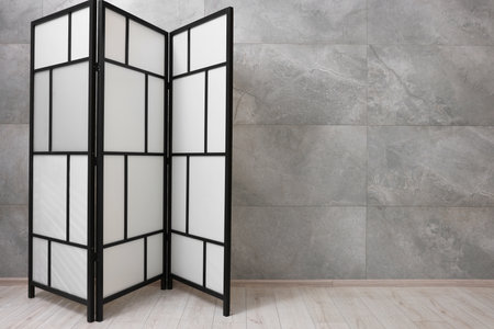 Stylish folding screen near grey wall indoors, space for text. Interior elementの写真素材