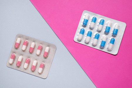 Different antibiotic pills in blisters on color background, flat lay