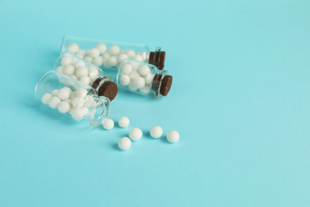 Homeopathy. Glass bottles with pills on light blue background, space for textの写真素材