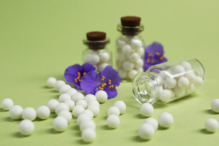 Bottles with homeopathic remedy and flowers on light green background, closeupの写真素材
