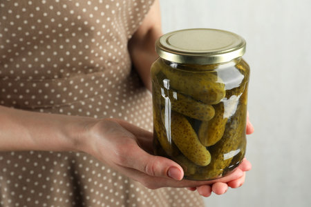 Woman holding jar with pickled cucumbers on gray background, closeupの写真素材
